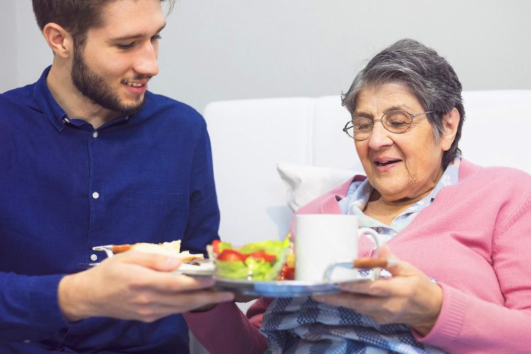 Dayspring Villa Assisted Living Community in Denver, CO - dayspring villa caregiver giving resident tray of food