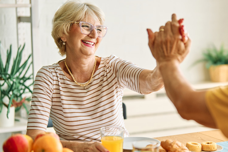 Dayspring Villa Assisted Living Community in Denver, CO - dsv senior woman eating breakfast and high fiving a friend